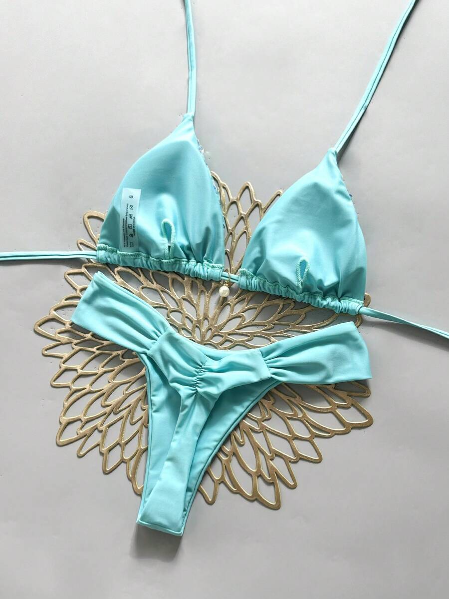 Women's 2-piece triangle cup bikini set in solid color featuring woven pearl shell decoration, halter neckline, and high-waist side-tie ruched bottoms.