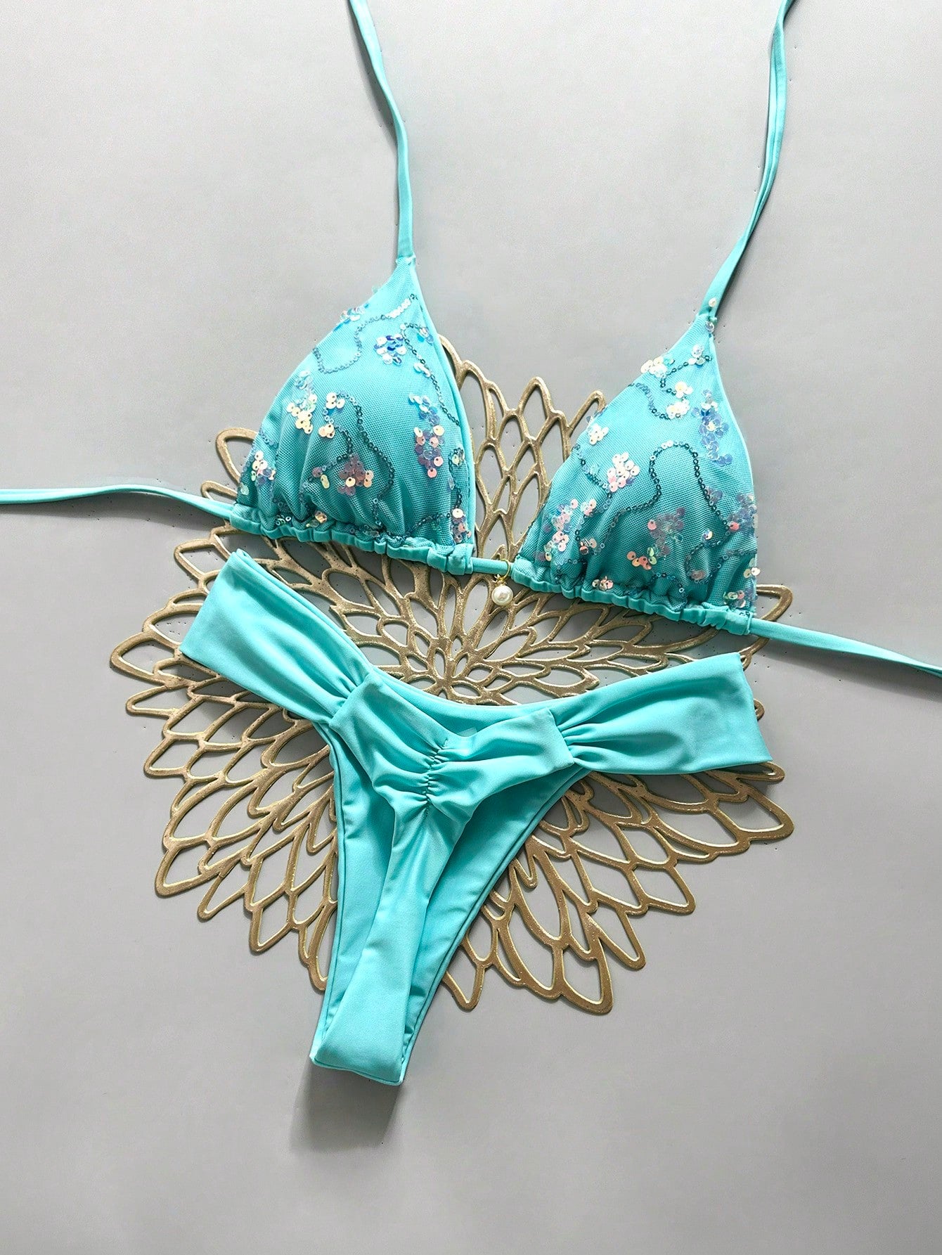 Women's 2-piece triangle cup bikini set in solid color featuring woven pearl shell decoration, halter neckline, and high-waist side-tie ruched bottoms.