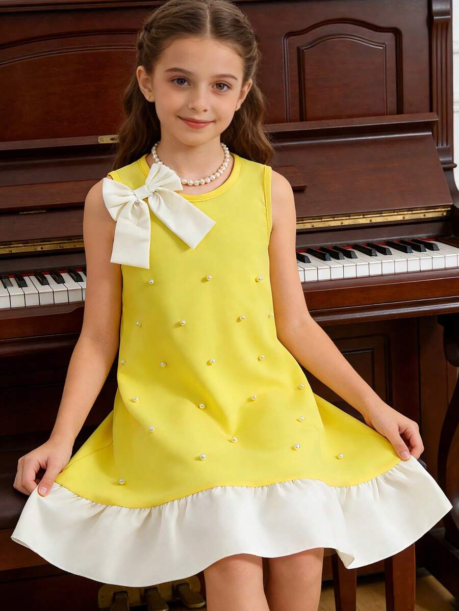 Yellow sleeveless colorblock dress for girls featuring a round neck, ruffle hem, and front bow detail.