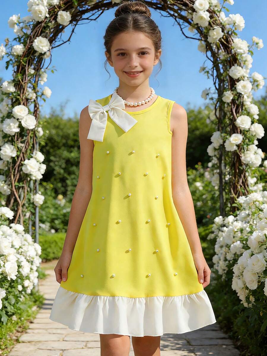 Yellow sleeveless colorblock dress for girls featuring a round neck, ruffle hem, and front bow detail.