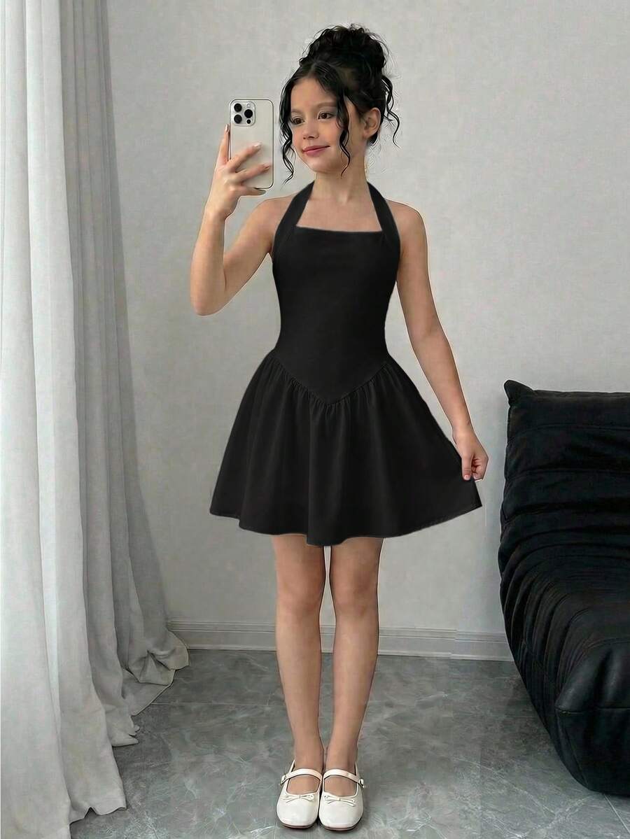 Black sleeveless halter polka dot mini dress for tween girls featuring a high waist and flared hem