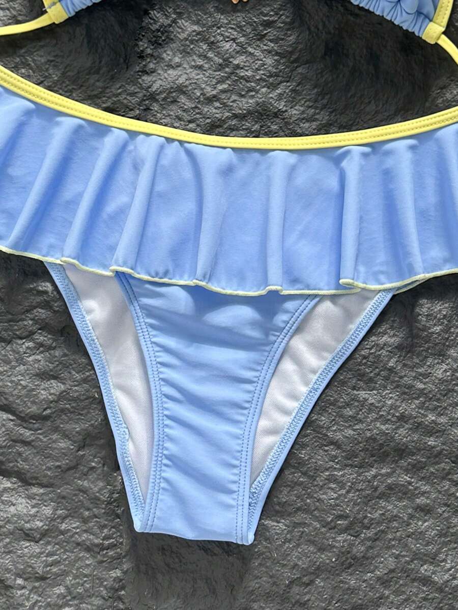Women's 70s retro black and white polka dot bikini set featuring a halter triangle top and ultra low waist bottoms.