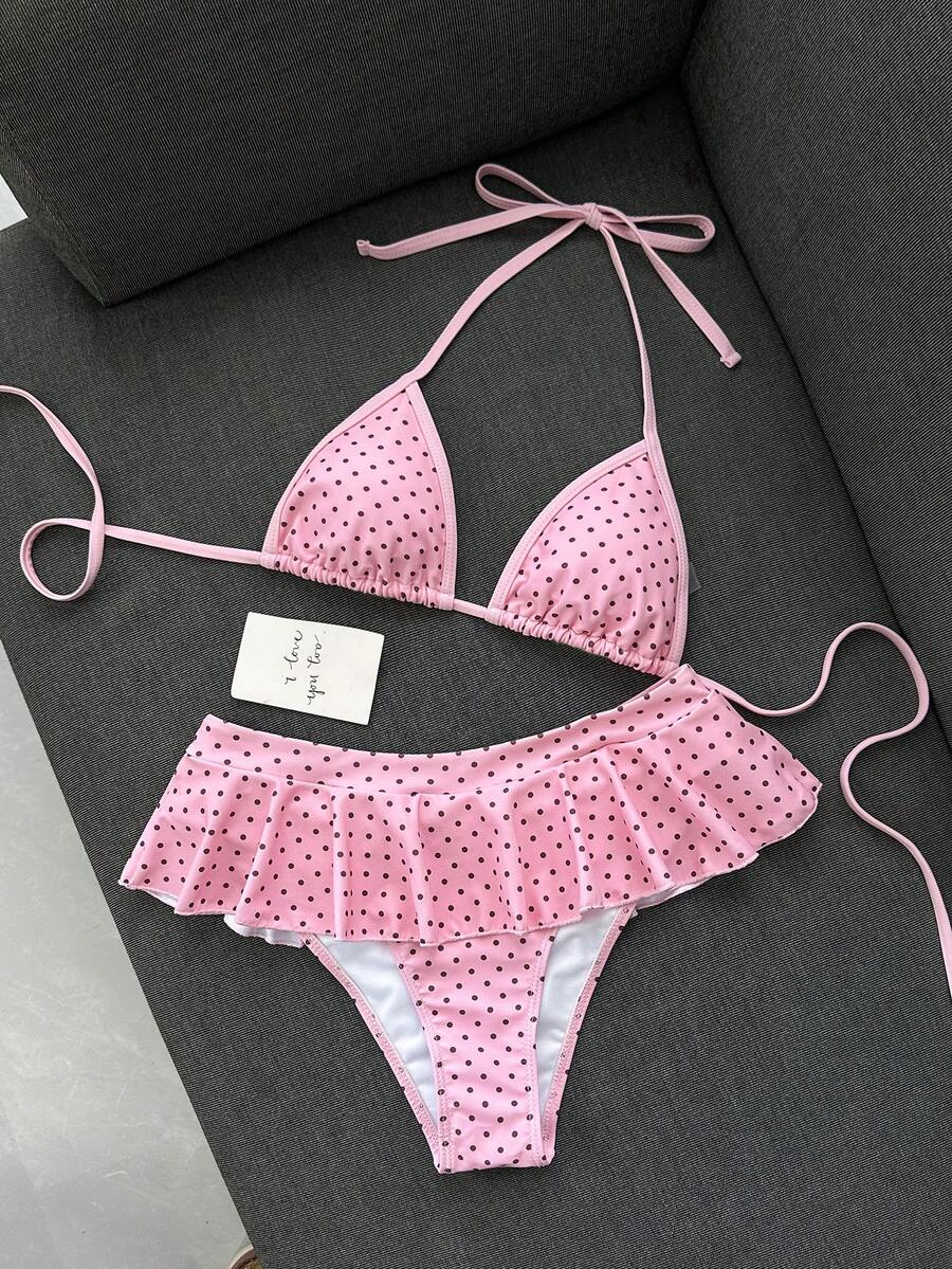Women's 70s retro black and white polka dot bikini set featuring a halter triangle top and ultra low waist bottoms.