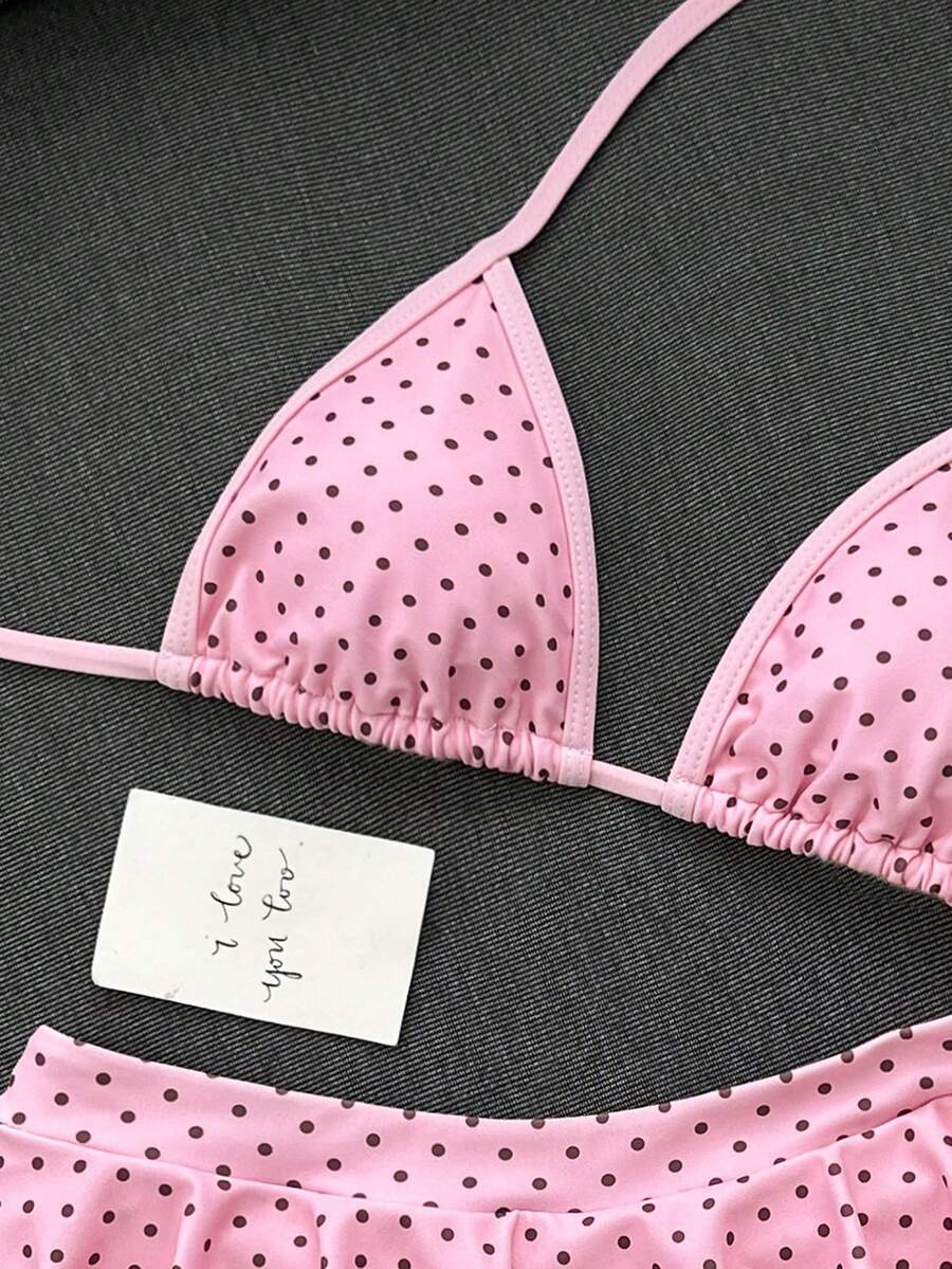 Women's 70s retro black and white polka dot bikini set featuring a halter triangle top and ultra low waist bottoms.