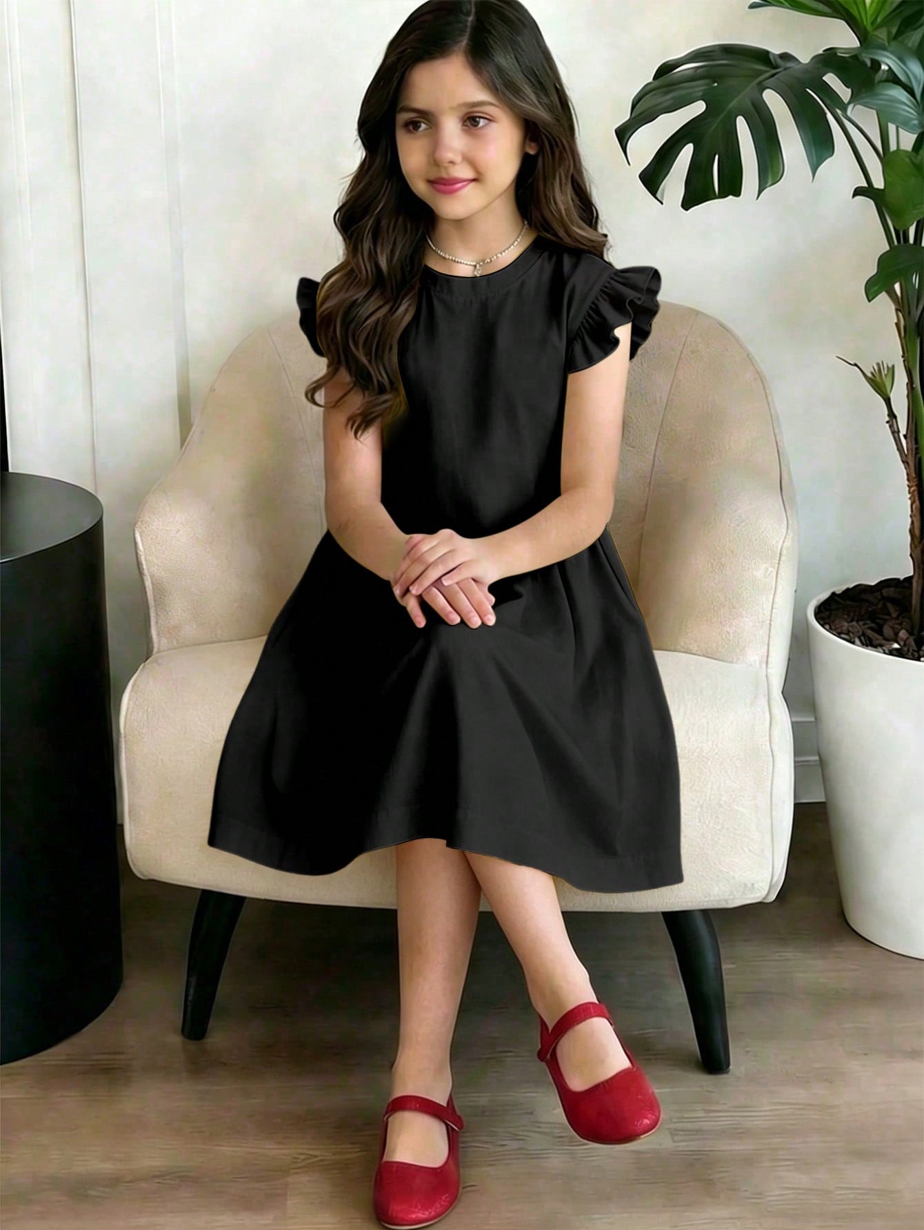 Girls black ruffle sleeve midi dress featuring a loose fit tunic silhouette, round neckline, button details, and short flounce sleeves.