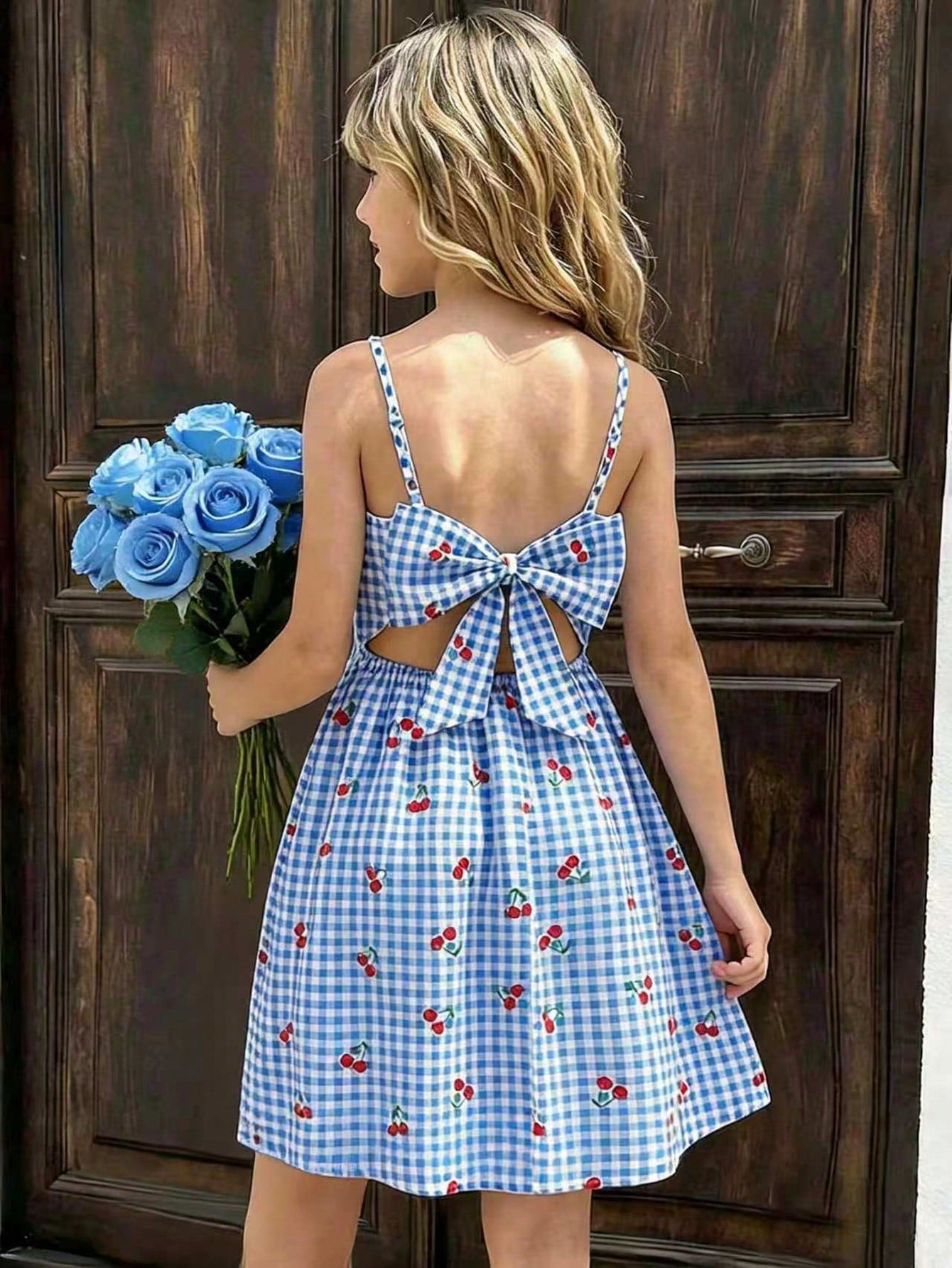 Tween girl wearing an apricot floral print sleeveless mini cami dress featuring spaghetti straps, a shirred high waist, flounce hem, and a bow back detail.