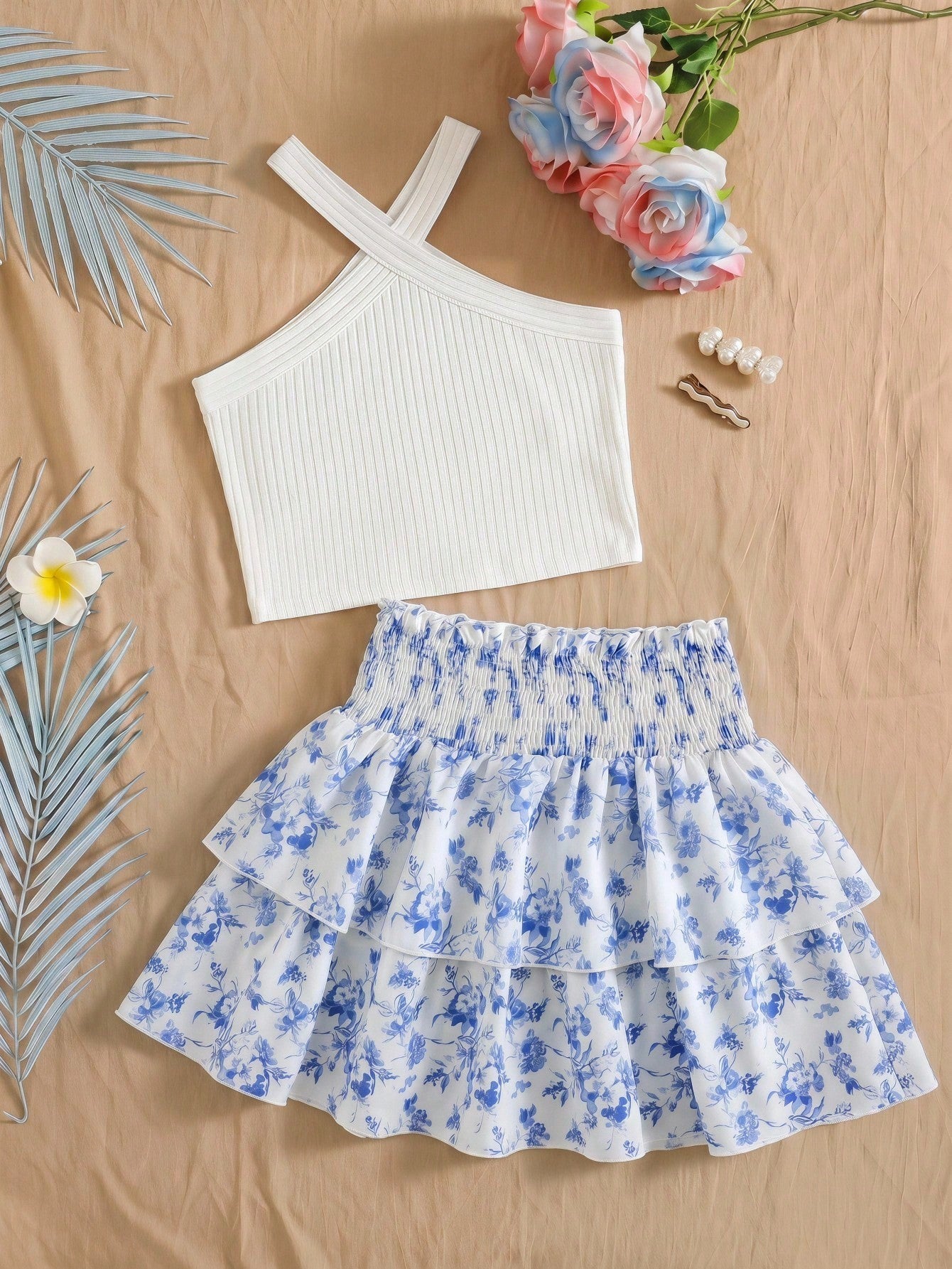 Tween girls blue and white 2-piece set with a striped halter neck vest top and a floral high-waist tiered paperbag skirt.