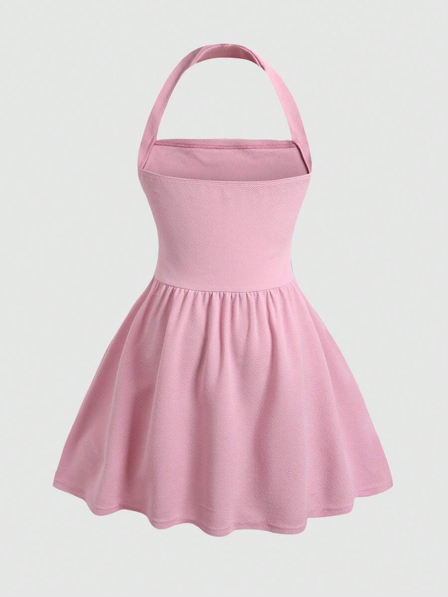Black sleeveless halter polka dot mini dress for tween girls featuring a high waist and flared hem