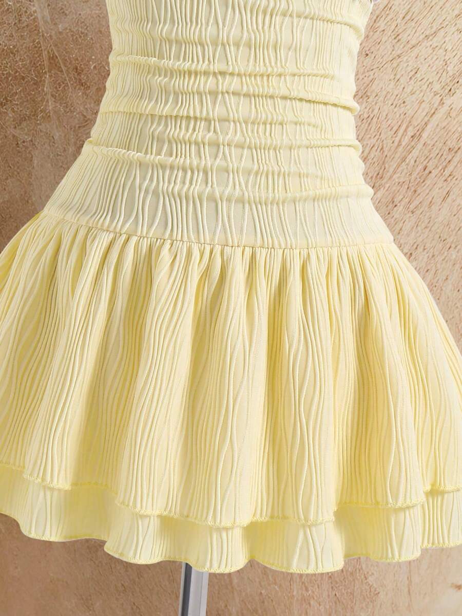 Tween girl black mini dress with halter neckline, backless design, tiered layer detail, high waist, flounce hem, and sleeveless slim fit.