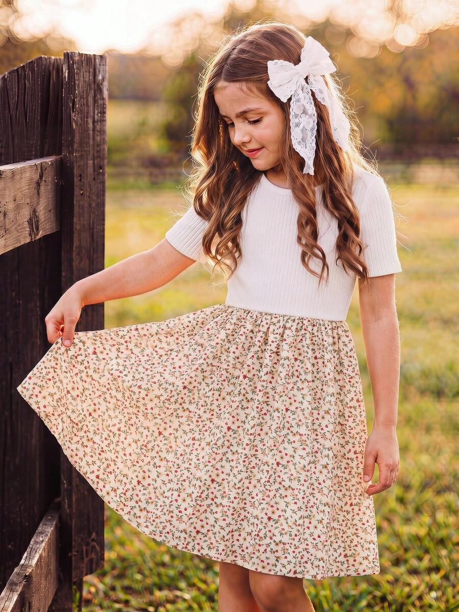 Tween girl wearing an apricot short sleeve A-line dress featuring a round neck, high waist with a belt, and flared hem.