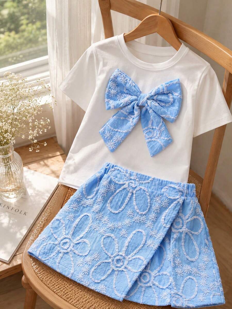 Tween girls 2-piece blue outfit featuring a short sleeve round neck t-shirt with a bow front detail and an asymmetric wrap skort.