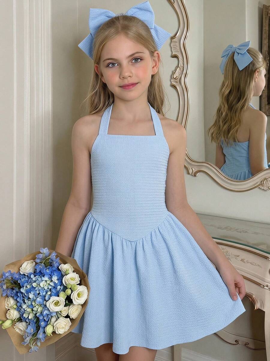 Black sleeveless halter polka dot mini dress for tween girls featuring a high waist and flared hem
