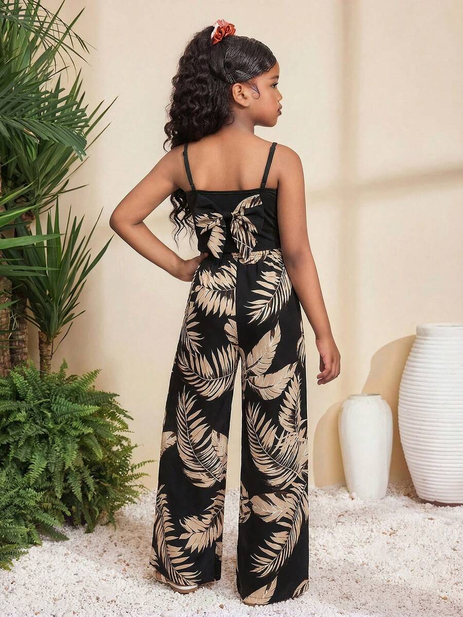 Tween girl wearing a black sleeveless spaghetti strap camisole top with 3D bow decor and matching leopard print wide leg long pants.