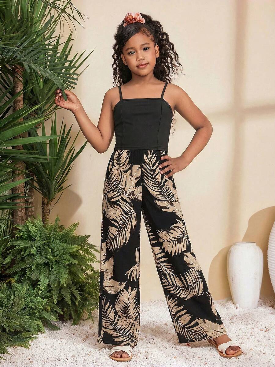 Tween girl wearing a black sleeveless spaghetti strap camisole top with 3D bow decor and matching leopard print wide leg long pants.
