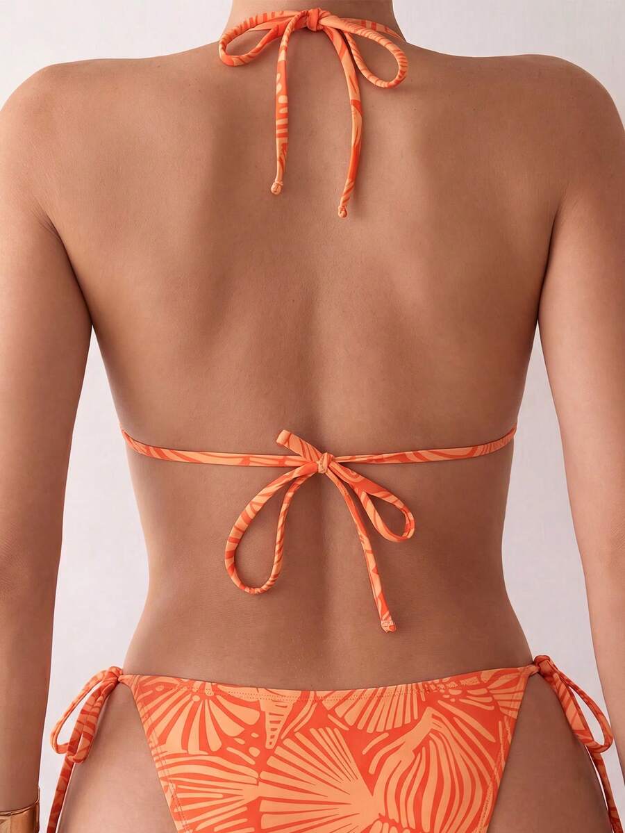 Women's black two-piece bikini set featuring a halter neck with a colorful sun pendant, triangle cups, and high-cut tie-side bottoms.