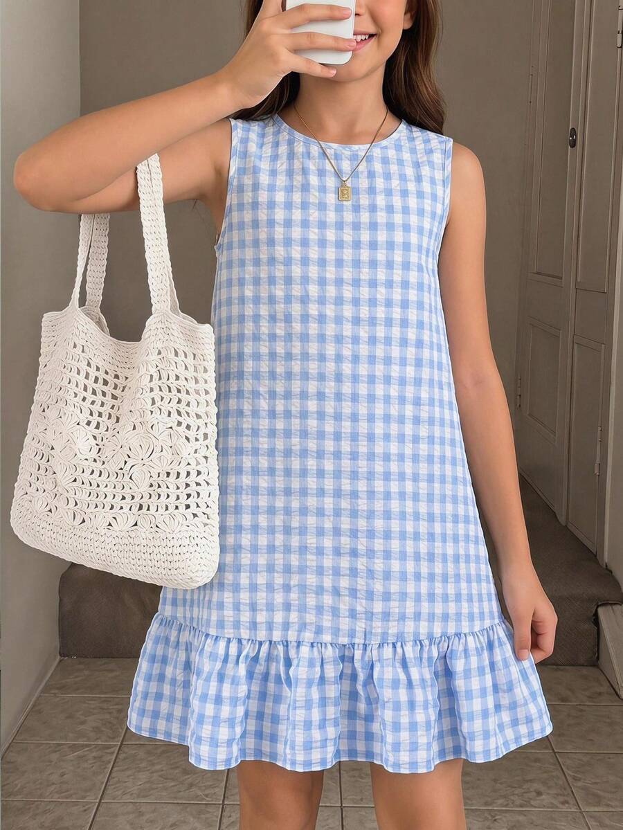 Tween girl wearing a sleeveless black tunic dress featuring a round neck, contrast lace details, and a straight hem.