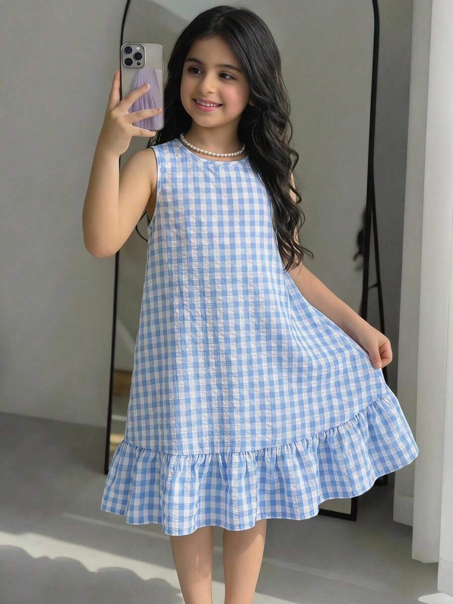 Tween girl wearing a sleeveless black tunic dress featuring a round neck, contrast lace details, and a straight hem.