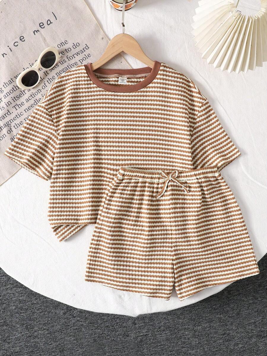 Tween girl wearing a black and white striped drop-shoulder crew neck t-shirt with bow embroidery paired with matching tie-waist shorts.