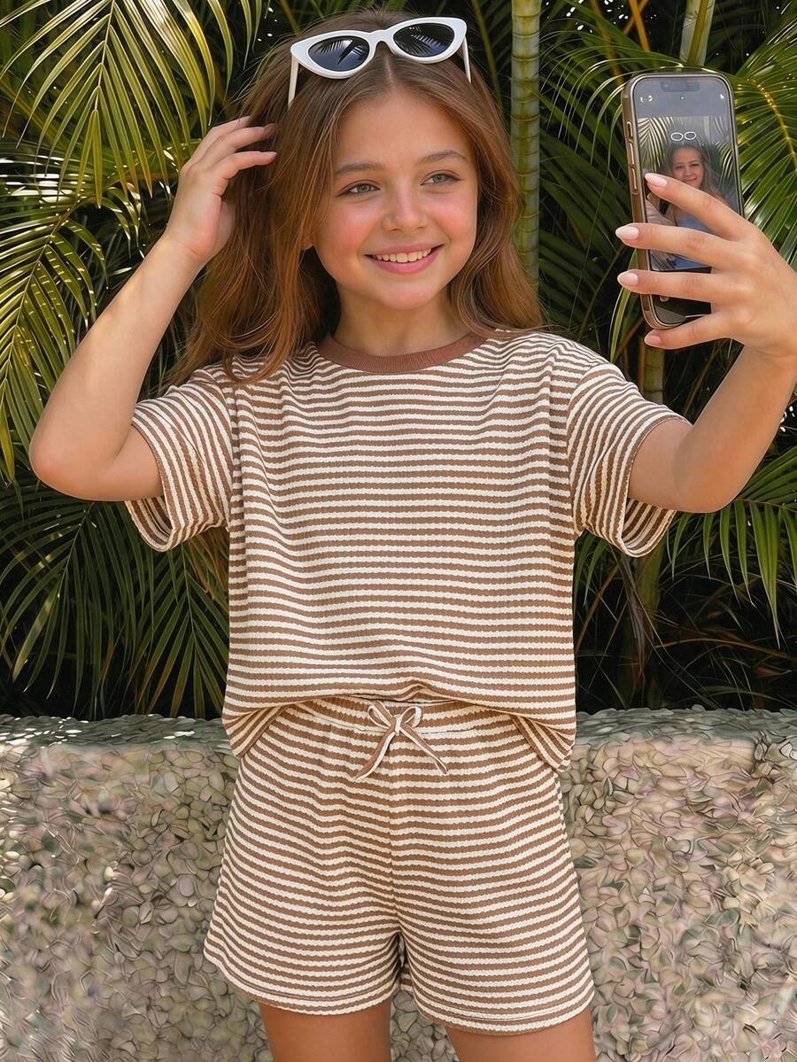 Tween girl wearing a black and white striped drop-shoulder crew neck t-shirt with bow embroidery paired with matching tie-waist shorts.