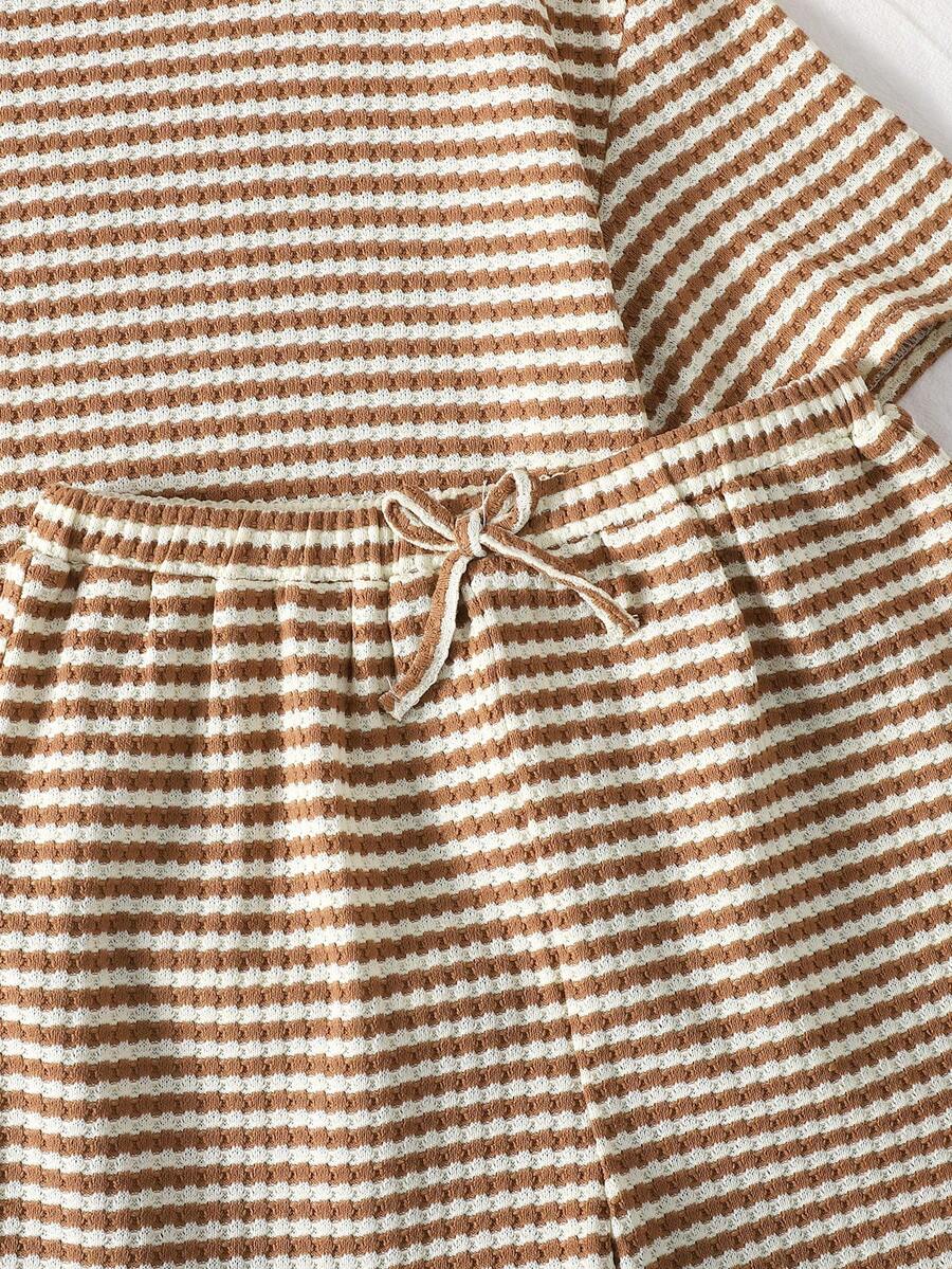 Tween girl wearing a black and white striped drop-shoulder crew neck t-shirt with bow embroidery paired with matching tie-waist shorts.