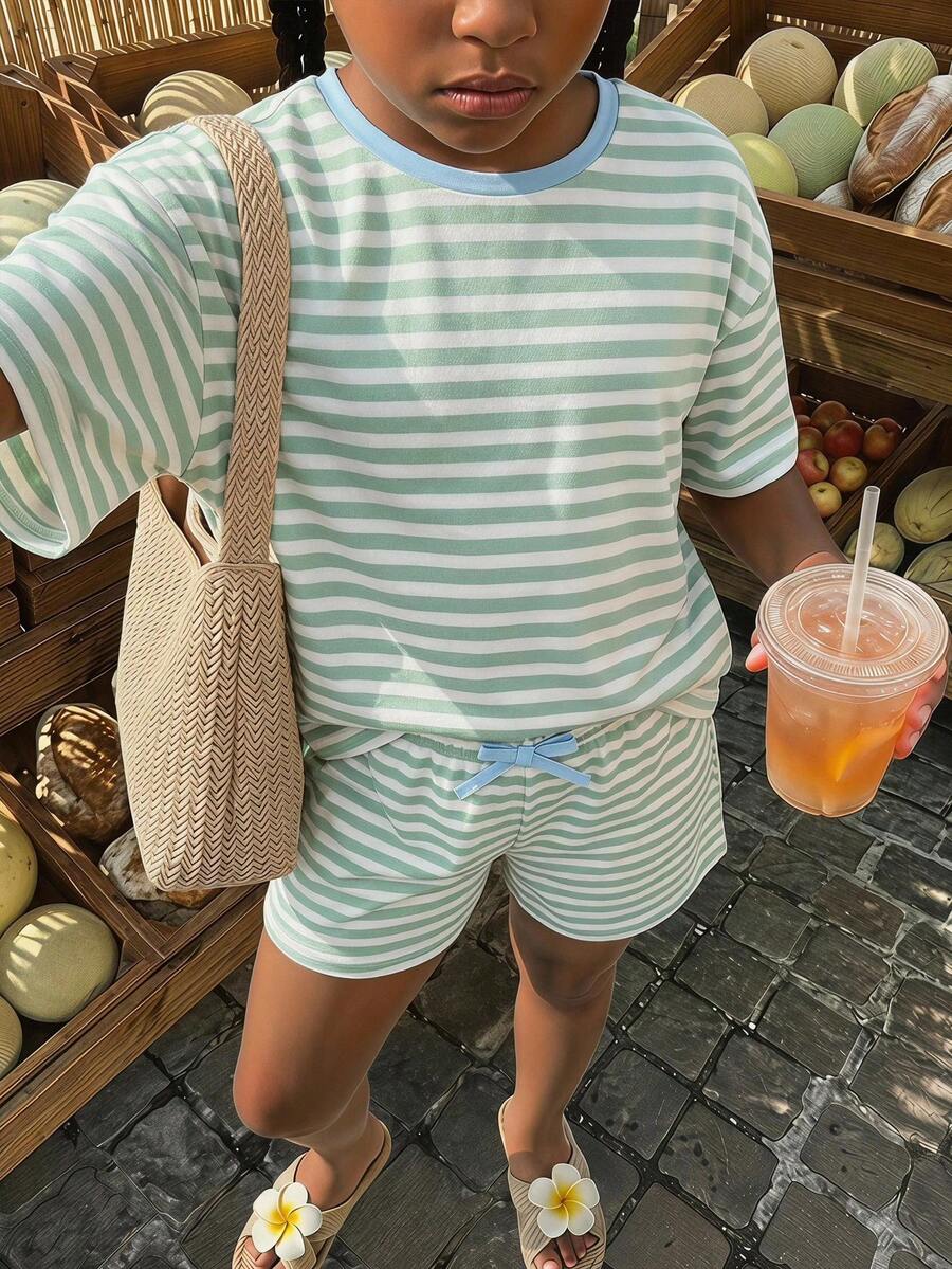 Tween girl wearing a black and white striped drop-shoulder crew neck t-shirt with bow embroidery paired with matching tie-waist shorts.