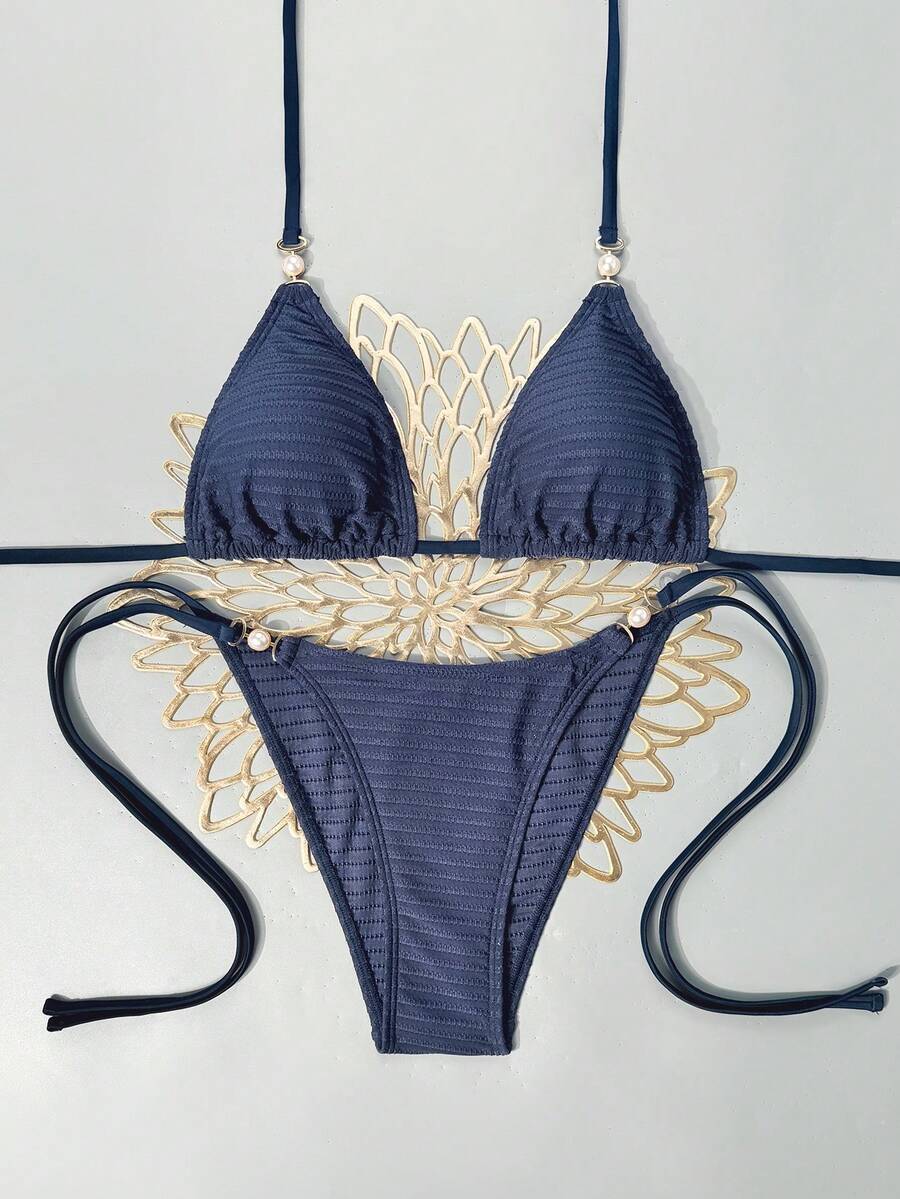 Women's black two-piece bikini set featuring a halter neck with a colorful sun pendant, triangle cups, and high-cut tie-side bottoms.