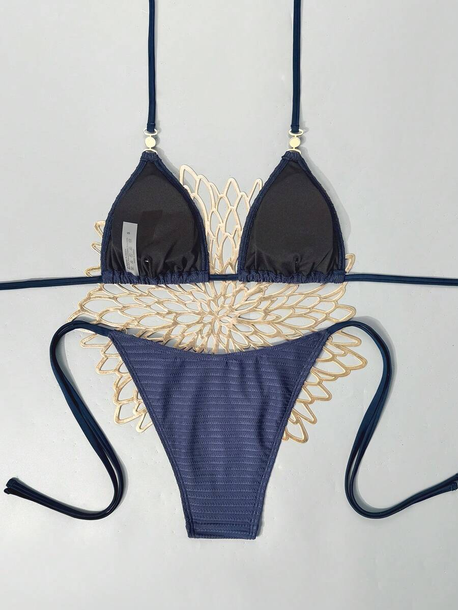 Women's black two-piece bikini set featuring a halter neck with a colorful sun pendant, triangle cups, and high-cut tie-side bottoms.