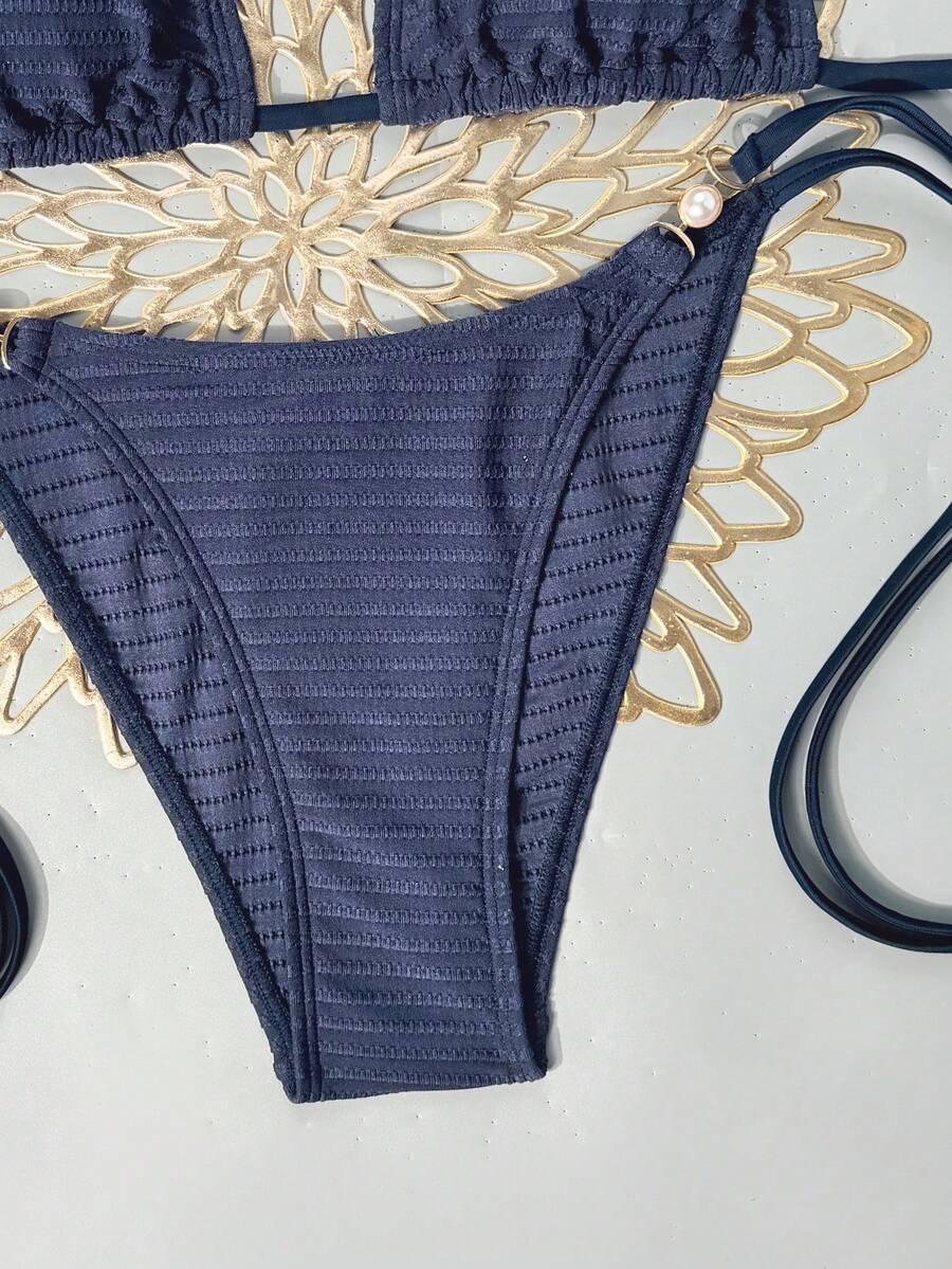 Women's black two-piece bikini set featuring a halter neck with a colorful sun pendant, triangle cups, and high-cut tie-side bottoms.