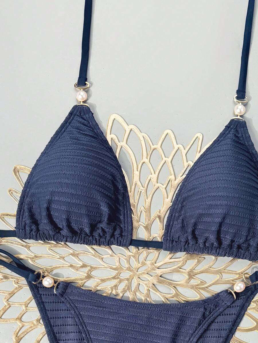 Women's black two-piece bikini set featuring a halter neck with a colorful sun pendant, triangle cups, and high-cut tie-side bottoms.