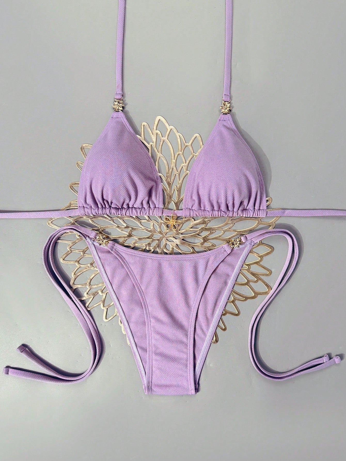 Women's black two-piece bikini set featuring a halter neck with a colorful sun pendant, triangle cups, and high-cut tie-side bottoms.