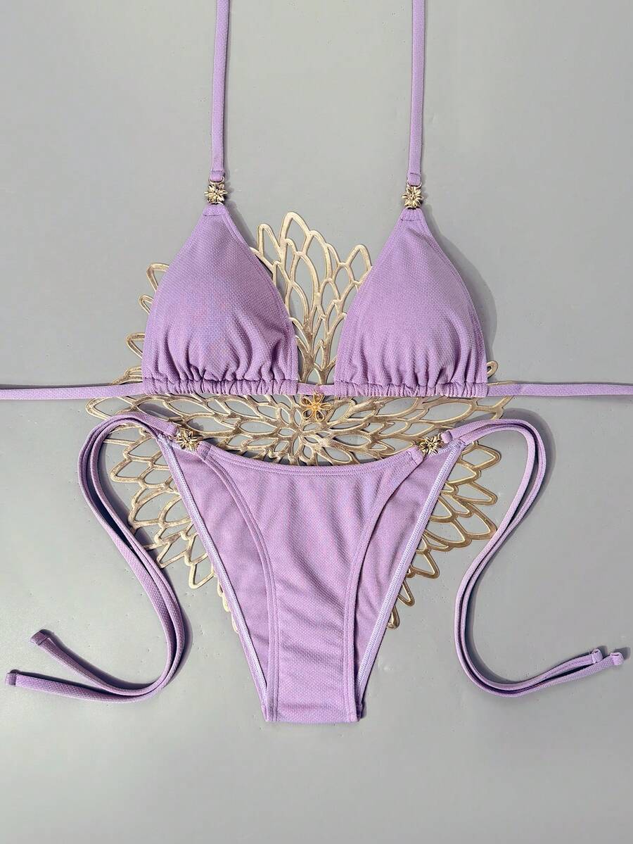 Women's black two-piece bikini set featuring a halter neck with a colorful sun pendant, triangle cups, and high-cut tie-side bottoms.