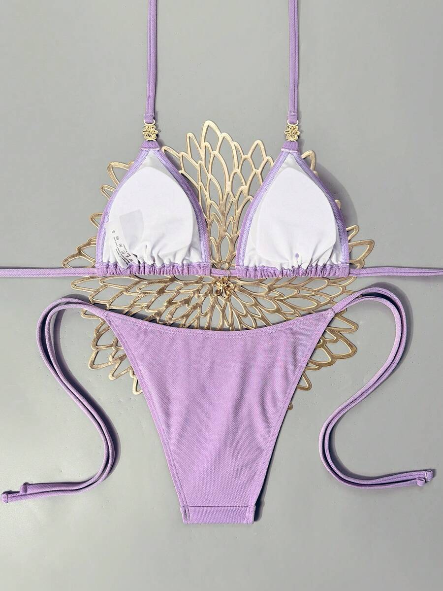 Women's black two-piece bikini set featuring a halter neck with a colorful sun pendant, triangle cups, and high-cut tie-side bottoms.