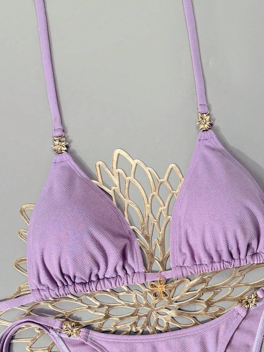 Women's black two-piece bikini set featuring a halter neck with a colorful sun pendant, triangle cups, and high-cut tie-side bottoms.