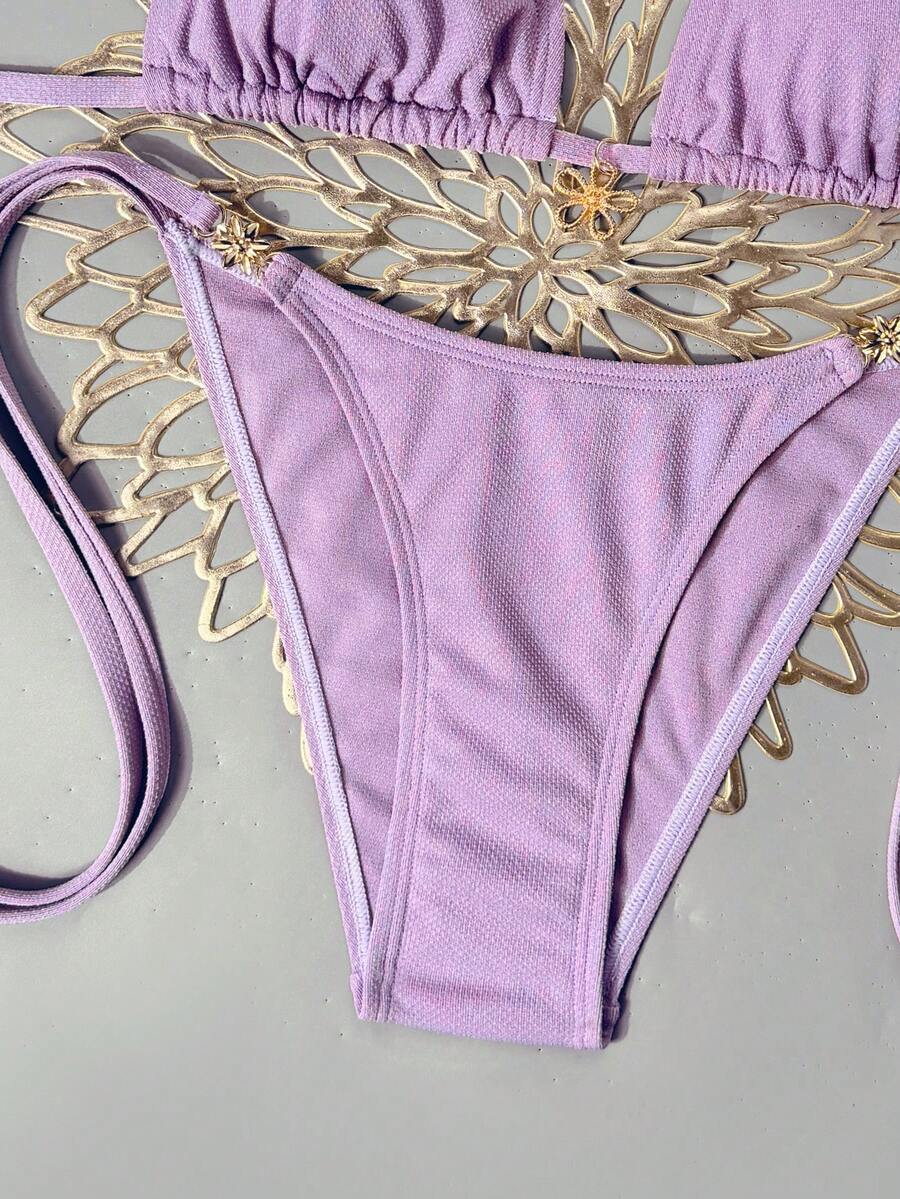 Women's black two-piece bikini set featuring a halter neck with a colorful sun pendant, triangle cups, and high-cut tie-side bottoms.