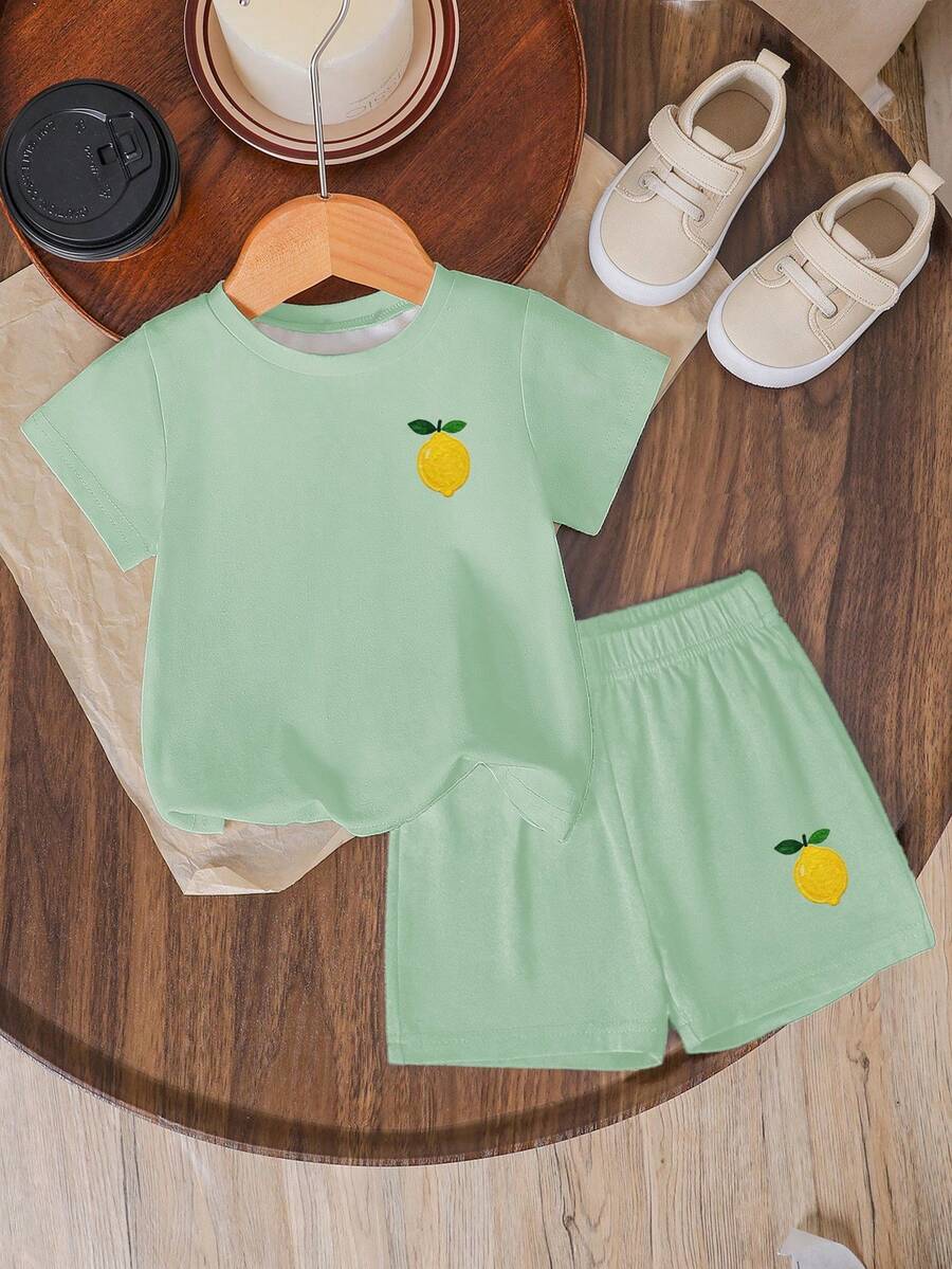 Tween girls two-piece green summer outfit featuring a fruit print short sleeve round neck t-shirt and matching track shorts with pockets.