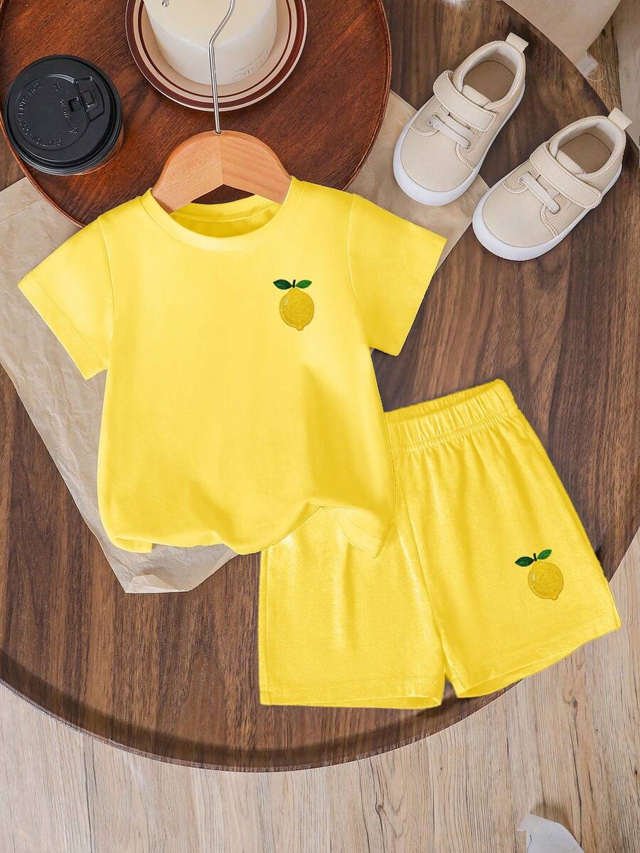 Tween girls two-piece green summer outfit featuring a fruit print short sleeve round neck t-shirt and matching track shorts with pockets.