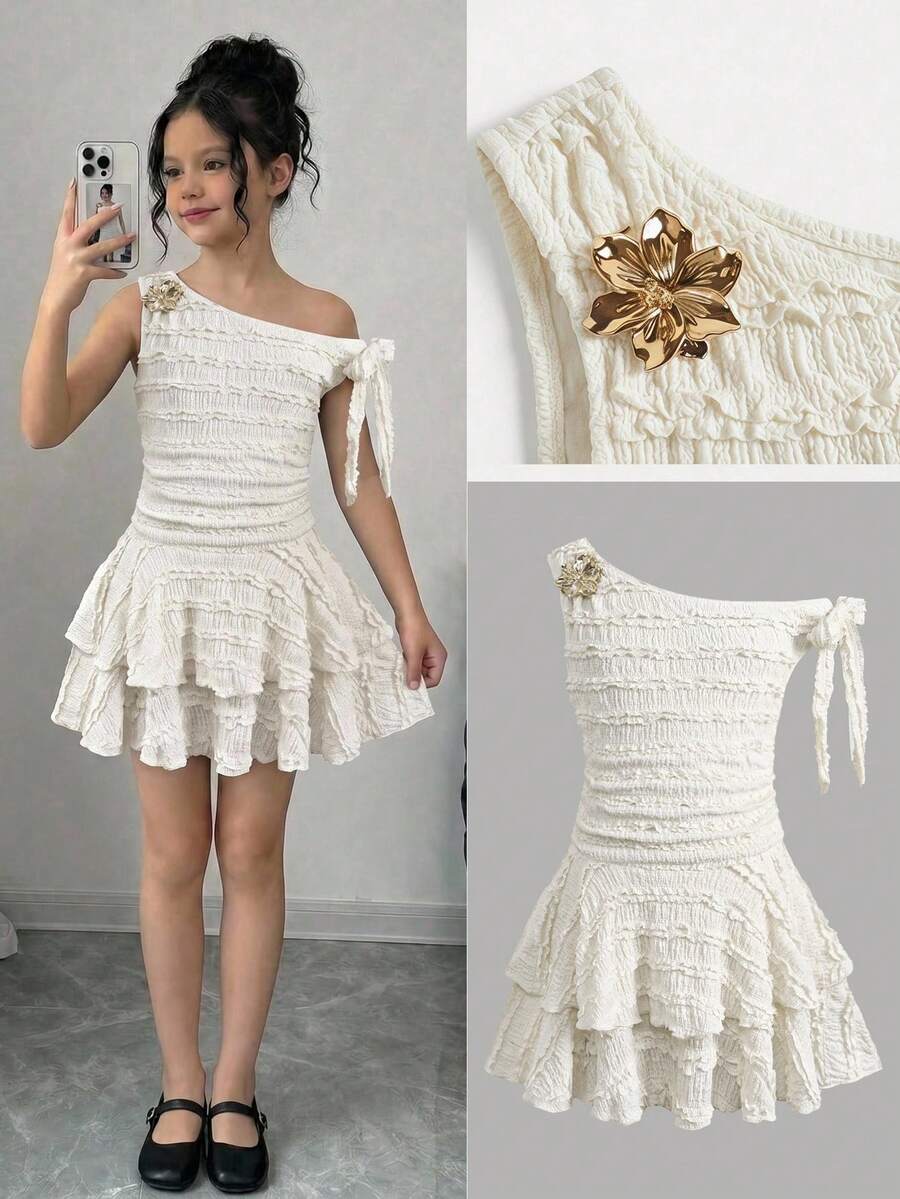 Tween girl wearing an apricot asymmetrical tiered sleeveless party dress with an A-line silhouette.