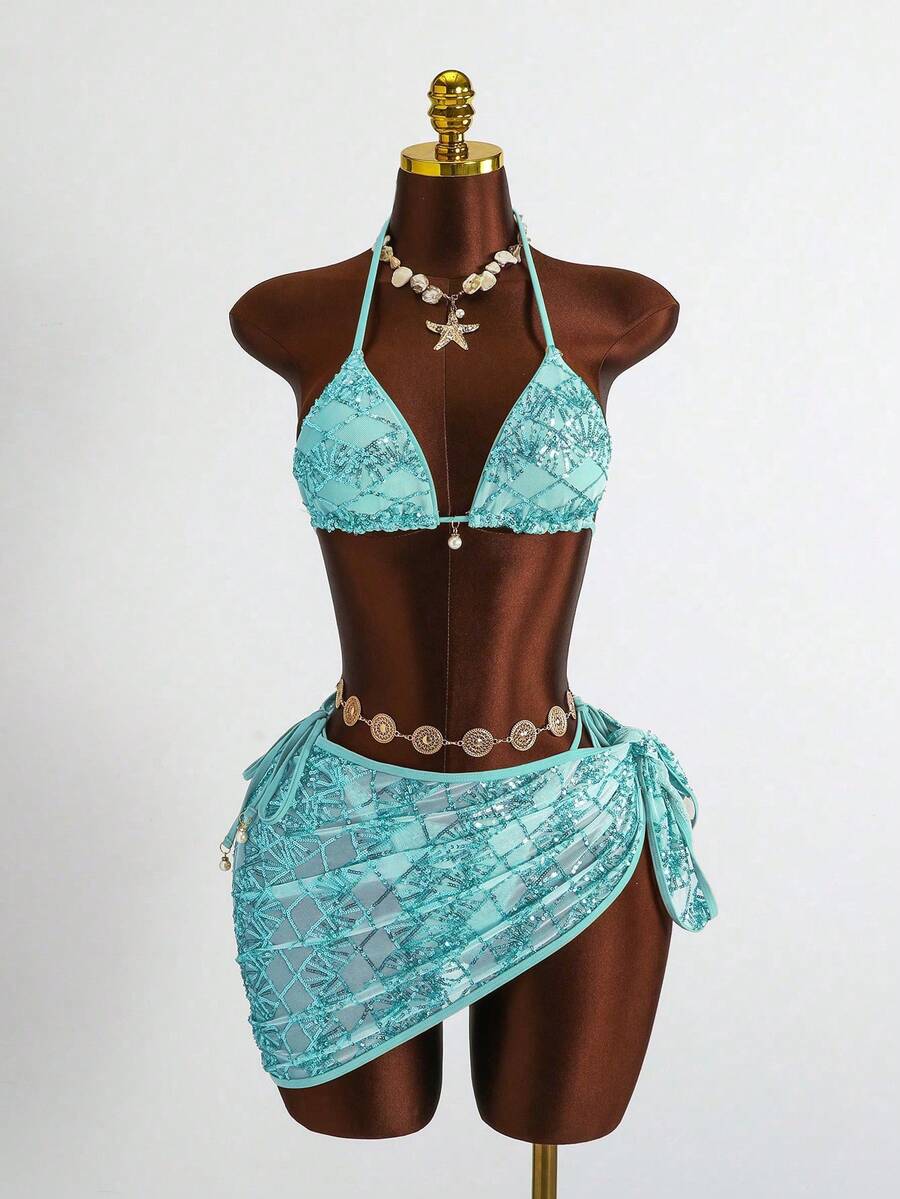 Women's 3-piece blue tropical shell print bikini set featuring a halter bralette top, low-waist tie-side bottom, and a matching sheer mesh cover-up skirt.
