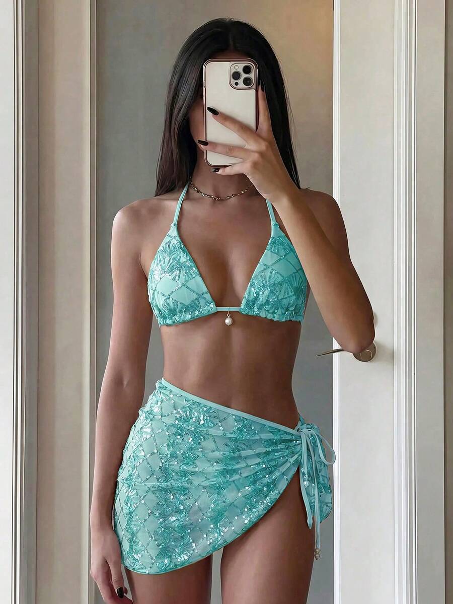 Women's 3-piece blue tropical shell print bikini set featuring a halter bralette top, low-waist tie-side bottom, and a matching sheer mesh cover-up skirt.