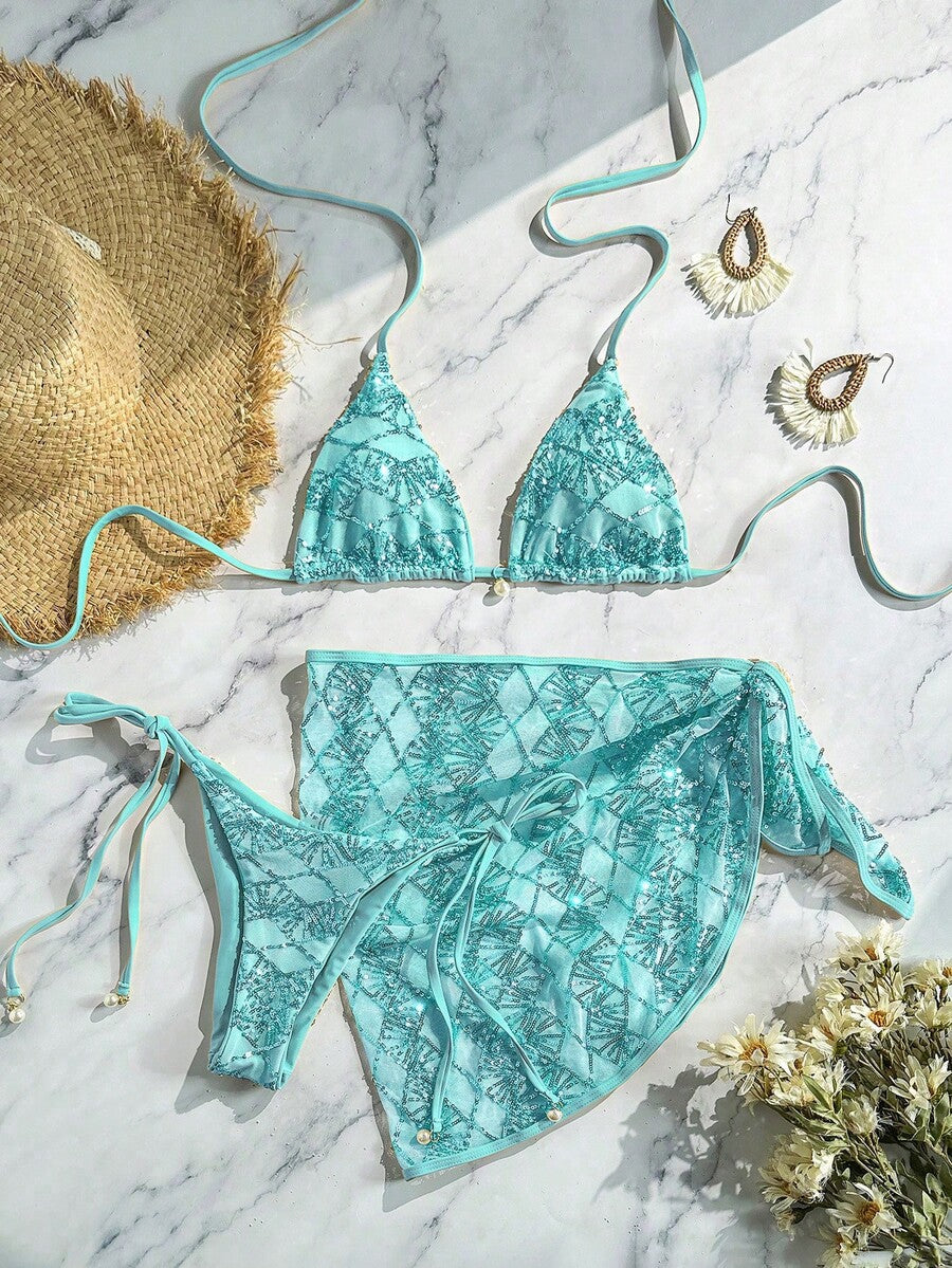 Women's 3-piece blue tropical shell print bikini set featuring a halter bralette top, low-waist tie-side bottom, and a matching sheer mesh cover-up skirt.