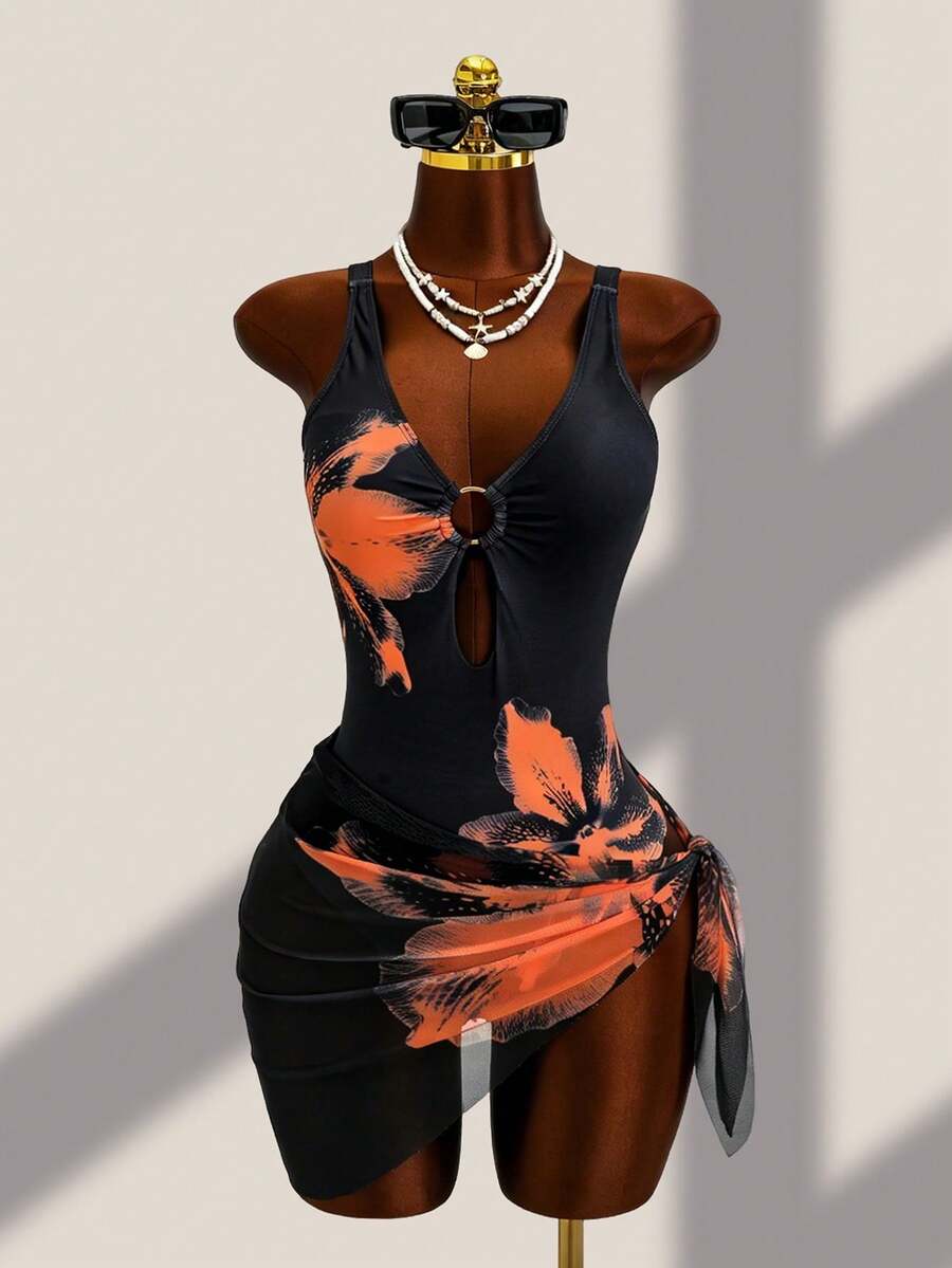Women's black floral print plunge neck one-piece swimsuit featuring cut-out detail paired with a matching knee-length mesh cover-up skirt