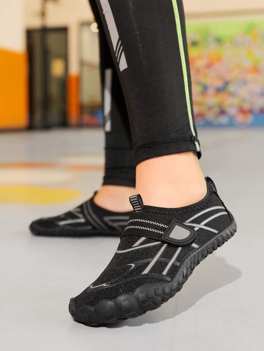 Black kids water shoes with graphic pattern, fabric upper, hook and loop closure, and non-slip rubber outsole for boys and girls.
