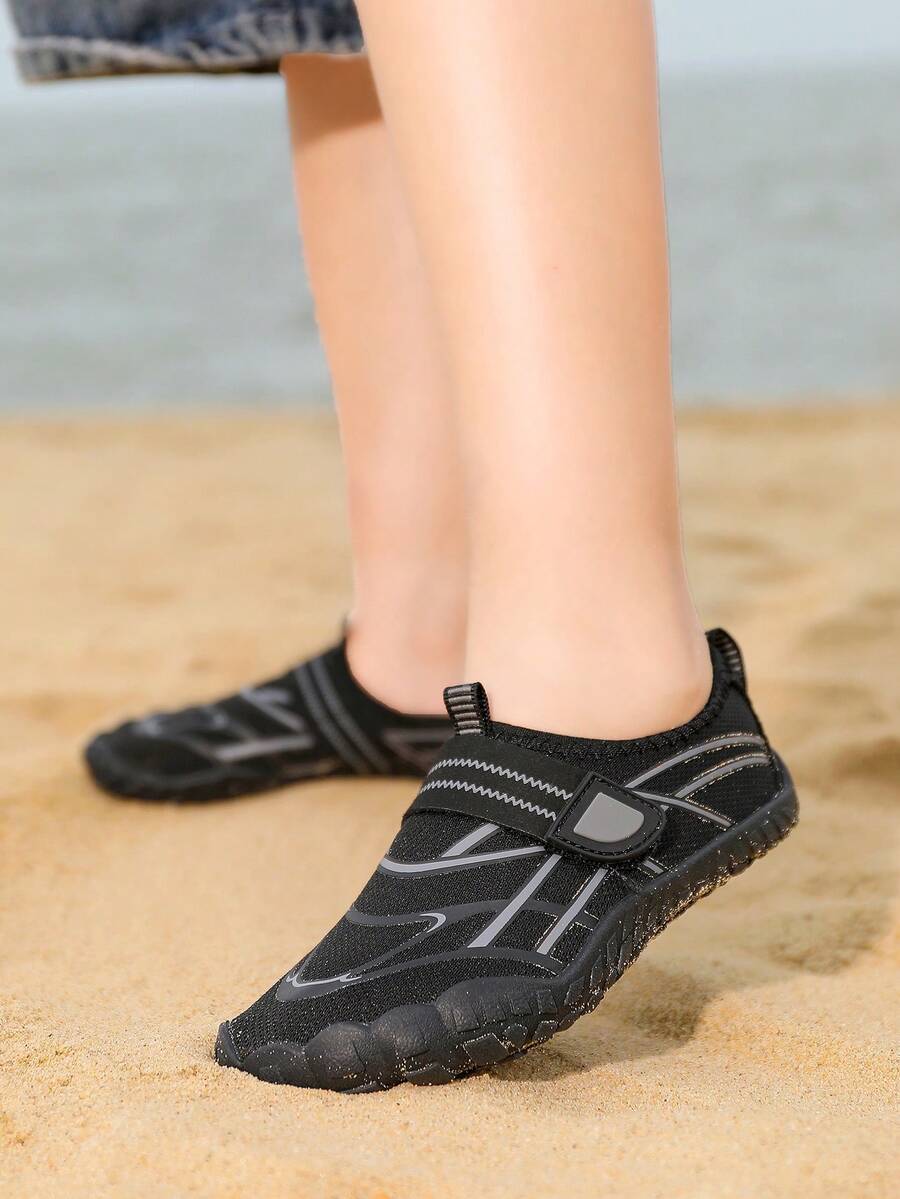 Black kids water shoes with graphic pattern, fabric upper, hook and loop closure, and non-slip rubber outsole for boys and girls.