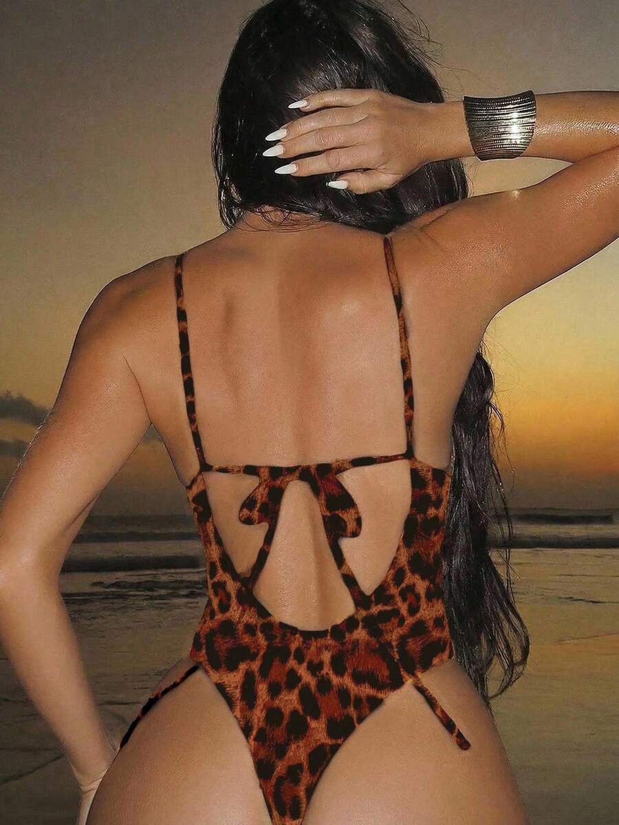 Women's black lace one-piece swimsuit featuring a deep V-neckline, spaghetti straps, backless tie-up detail, and thong bottom.