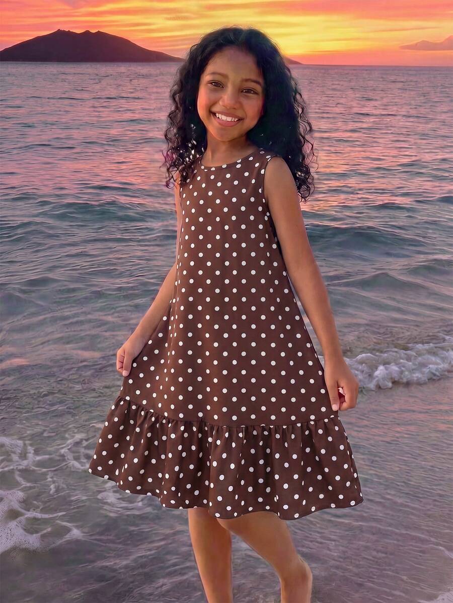 Tween girl wearing a sleeveless black tunic dress featuring a round neck, contrast lace details, and a straight hem.