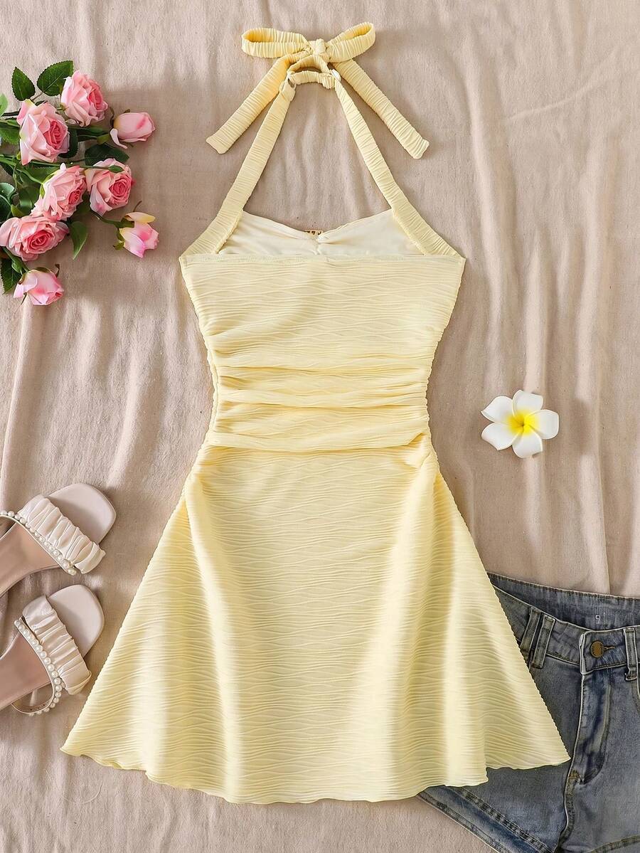 Tween girl yellow mini sundress with large pink floral hibiscus print, spaghetti straps, high waist, flared hem, and sleeveless cami style for summer beach wear