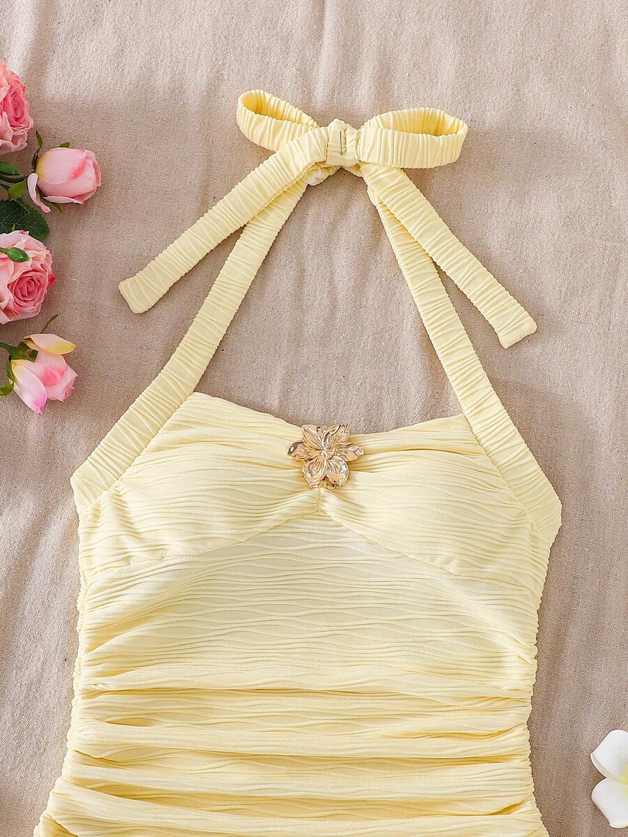 Tween girl yellow mini sundress with large pink floral hibiscus print, spaghetti straps, high waist, flared hem, and sleeveless cami style for summer beach wear