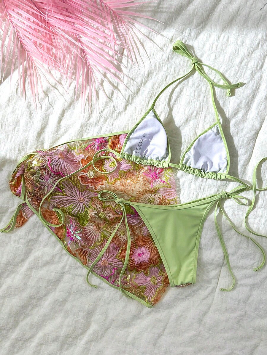 Women's 3-piece blue tropical shell print bikini set featuring a halter bralette top, low-waist tie-side bottom, and a matching sheer mesh cover-up skirt.