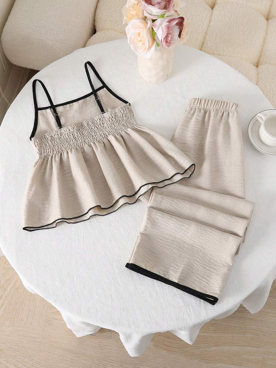 Tween girl wearing an apricot 2-piece outfit set featuring a shirred spaghetti strap short cami top and matching wide-leg long pants.