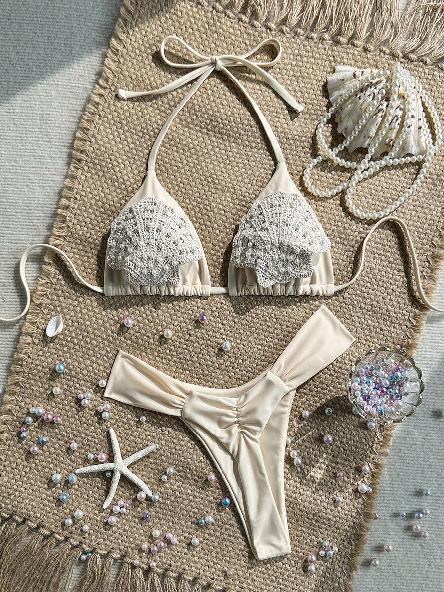Women's 2-piece triangle cup bikini set in solid color featuring woven pearl shell decoration, halter neckline, and high-waist side-tie ruched bottoms.